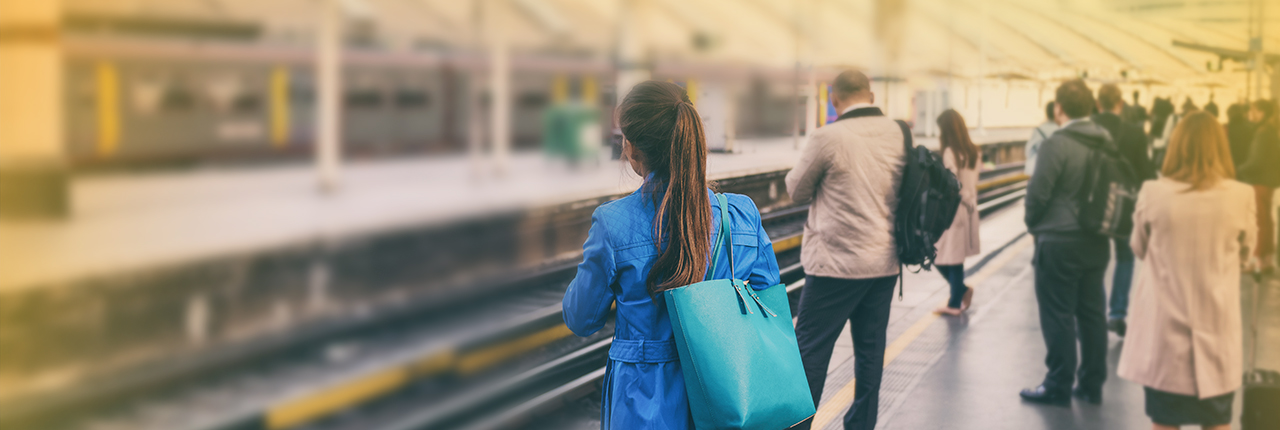 verschiedene Personen warten auf Bahnsteig, Rücken zur Kamera